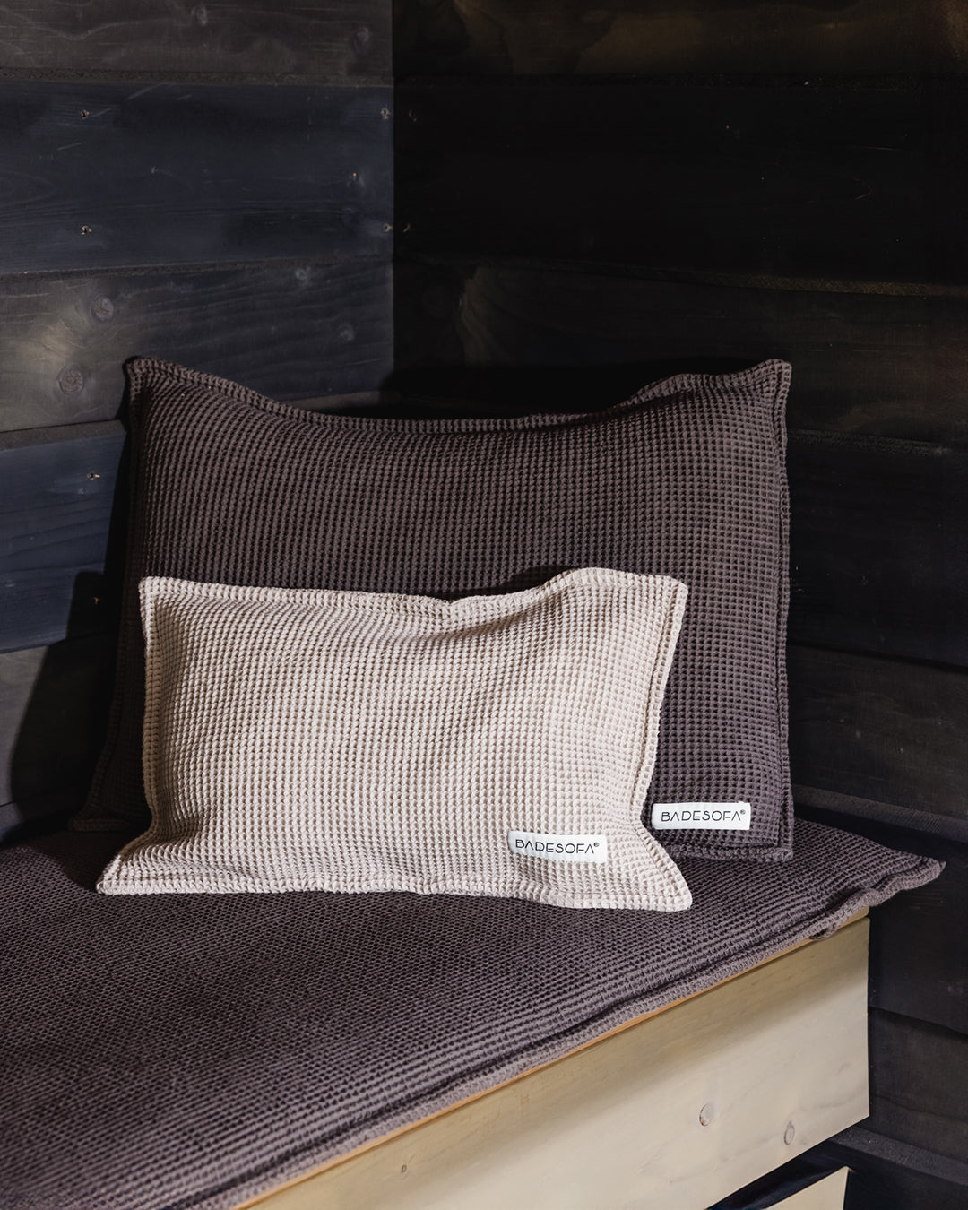 Kleines dekoratives Kopfkissen für die Sauna mit Füllung aus Zirbenspänen liegt in der Sauna, angelehnt an ein Saunakissen (in Taupr)