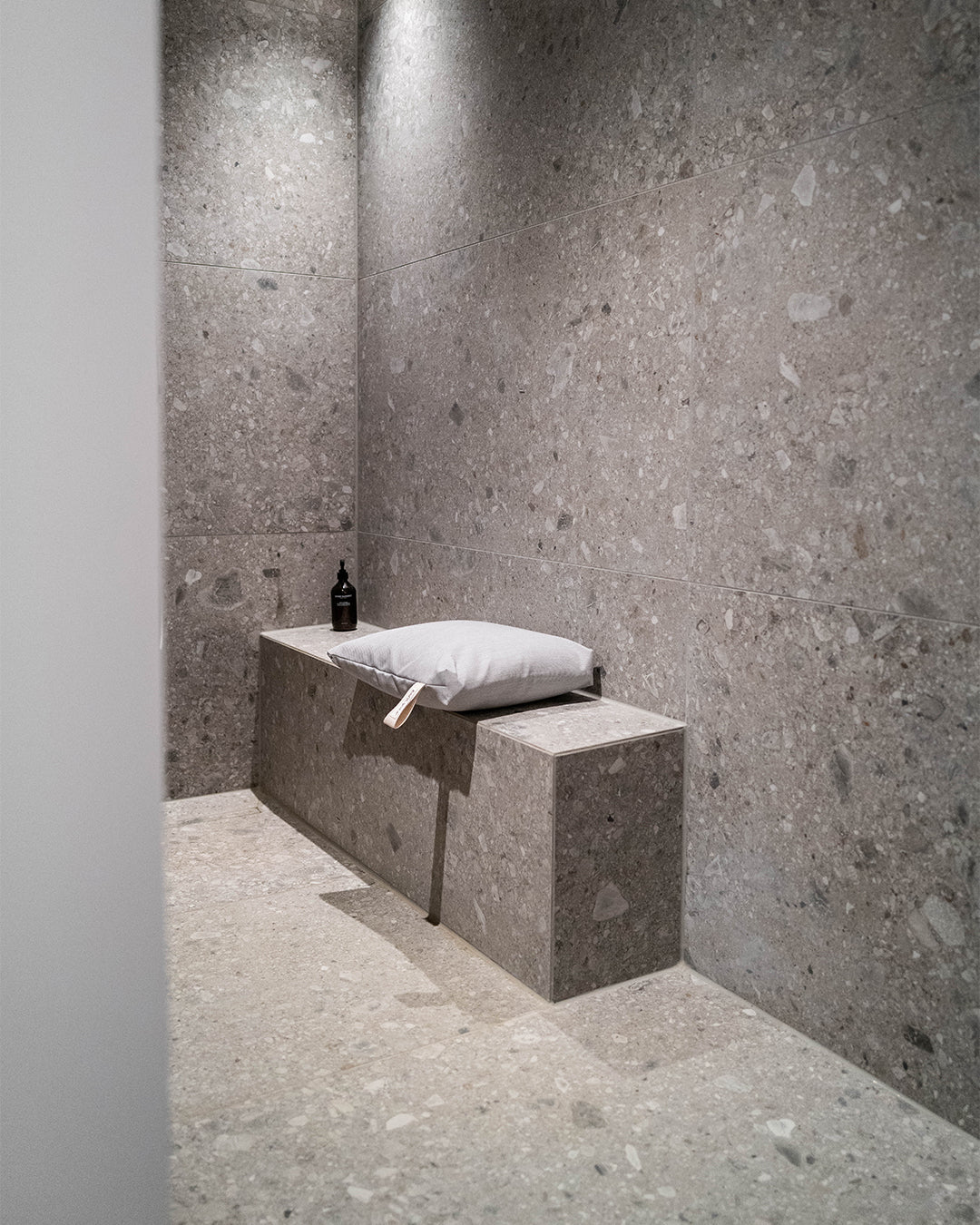 Badesofa Sitzkissen (Farbe: Grau) liegt auf einer gemauerten Bank in der Dusche.